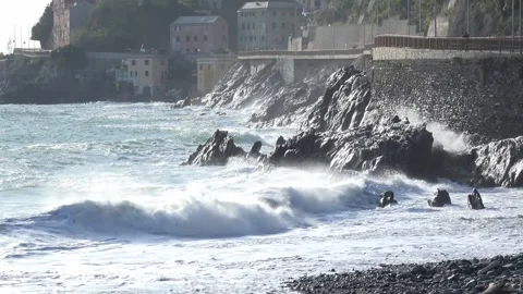 Waves crashing against the rocky cliffs of the coast on a sunny day, along t Stock Footage 293361575