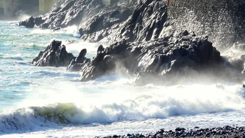 Waves crashing against the rocky cliffs of the coast on a sunny day, along t Stock Footage 293361931