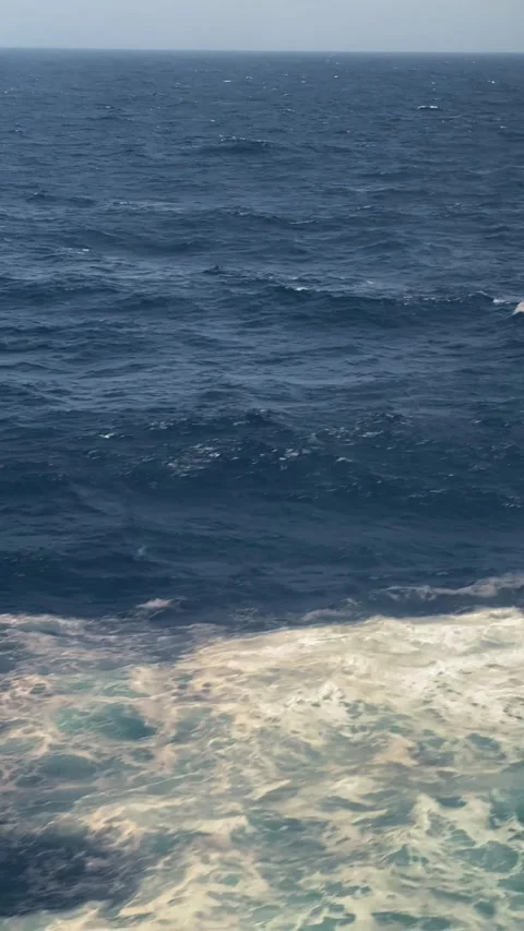 Waves crashing against the shore under clear skies during a sunny day at the bea Stock Footage 308256364