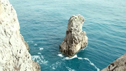 Waves crashing against a small rock in crystal-clear waters. Stock Footage 304667612