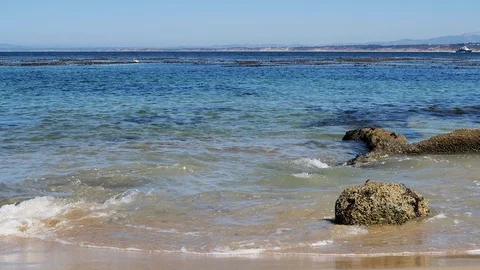 Waves crashing against small rocks on beach with space on left Stock Footage 96796443