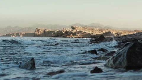 Waves crashing against stones on coast, rocks and hills. Dangerous place to Stock Footage 308009847