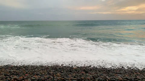 Waves crashing ashore beach in evening sunset on small rocks relaxing meditation Video stock 244952298
