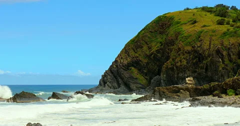 Waves crashing onto the beach with cliff in the background Stock Footage 53835589