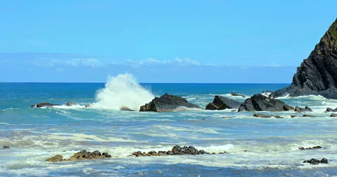 Waves crashing onto the beach with cliff in the background Stock Footage 53836389