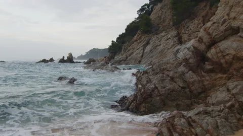 Waves crashing on the beach rocks on a cloudy day, in Spain Stock Footage 230096784