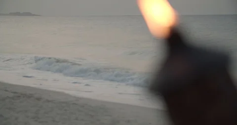 Waves Crashing In Behind Torch Flame at Sunset, Slow Motion Stock Footage 112428618