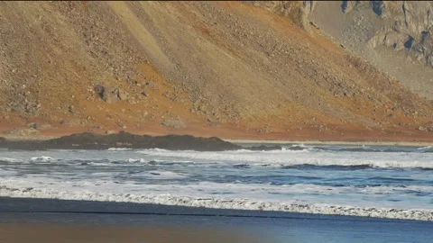Waves crashing on a black sand beach with a rocky mountain in Iceland Stock Footage 320200831
