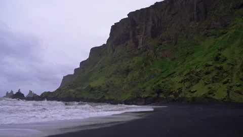 Waves crashing on black sand beach near lush mountains in Vik 動画素材 327082685