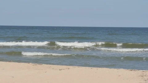 Waves crashing on an empty sandy beach against a blue sky. Stock Footage 222644608