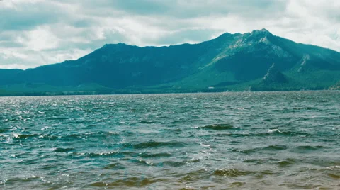 Waves crashing gently on quiet sandy beach. mountain background. 4K footage Stock Footage 64865973