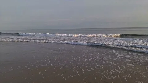 Waves crashing gently on a quiet sandy beach. Sunset time Vídeos de archivo 74938686
