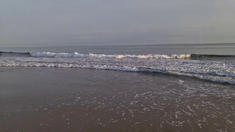 Waves crashing gently on a quiet sandy beach. Sunset time Vídeos de archivo 74938699