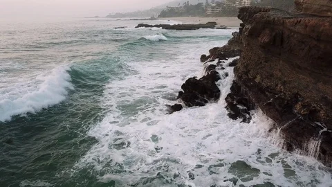 Waves crashing on large rock formation on an overcast winter day at Laguna Beach Stock Footage