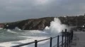Waves crashing over railings with hill in background, storm after hurricane HD Footage