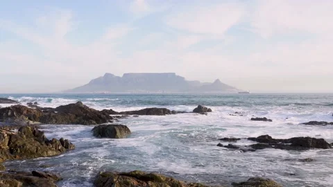 Waves crashing over rocks in front of Table Mountain 스톡 동영상 234630894