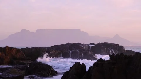 Waves crashing over rocks with Table Mountain behind Stock Footage 315761484