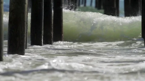 Waves crashing into pier pilings under pier Stock Footage 98142060