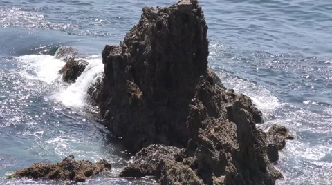 Waves crashing on rock in the ocean surging blue water over jagged enscarpmen Stock Footage 67581047