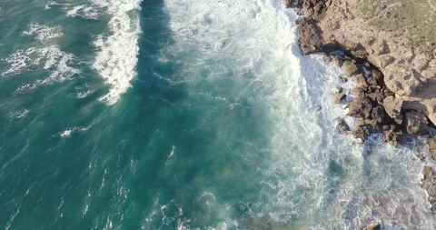 Waves crashing on rocks with a dirth path following alongside the shore Stock Footage 111774833
