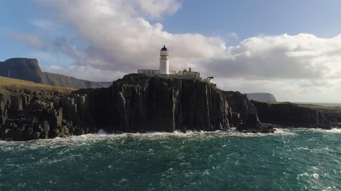 Waves crashing into rocks as lighthouse stands on top of cliff drone aerial 4K Stock Footage 104579629