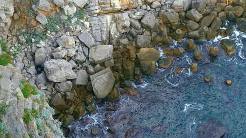 Waves crashing on the rocks. Top down view of clear sea on a sunny day Video stock 170159965