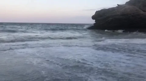 Waves crashing on a rocky beach with a large rock formation Stock Footage 317599188
