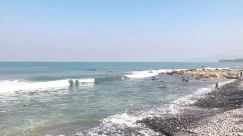 Waves crashing on a rocky pebble beach on a sunny day Stock Footage 342044688
