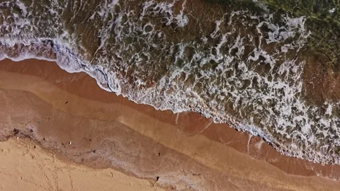 Waves crashing on sandy beach with clear blue water captured from above Stock Footage 325720846