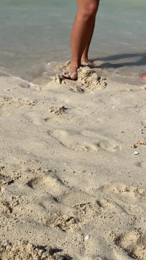 Waves crashing on a sandy beach. Close-up view. Feet of barefoot people walki Video stock 282800003