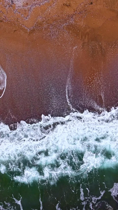 Waves crashing on a sandy beach at sunrise, creating a beautiful pattern of foam Stock Footage 331403251