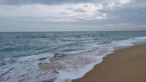 Waves crashing on sandy beach under cloudy sky with dynamic motion Stock Footage 321651118