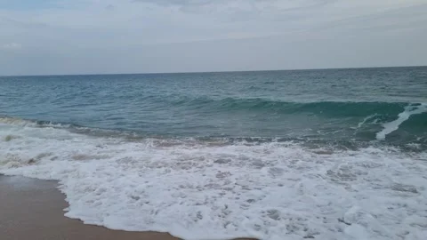 Waves crashing on sandy beach under calm cloudy autumn coastal sky Stock Footage 321651122