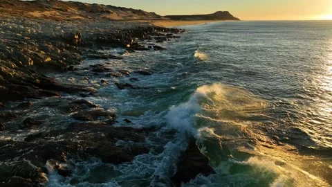 Waves crashing on shore while looking into a rising sun at dawn Stock Footage 236741855