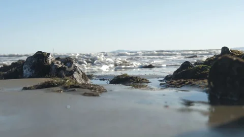 Waves crashing at some rocks on the beach – low angle Stock-Footage 122983622