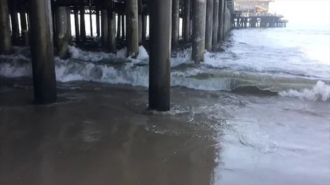 Waves crashing through poles under a pier slow motion Stock Footage 71750451