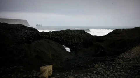 Waves Crashing Through a Small Arch by Kirkjufjara Beach Video stock 67646715