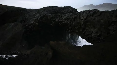 Waves Crashing Through a Small Arch by Kirkjufjara Beach Video stock 67763583