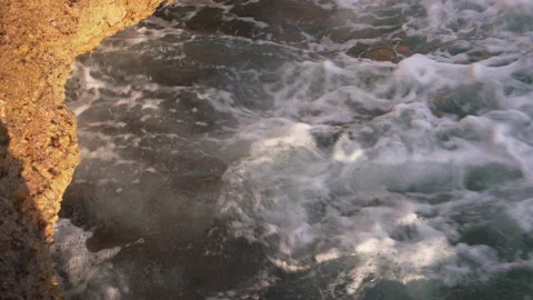 Waves crashing under rocks at sunset 스톡 동영상 131860728