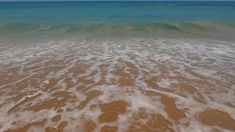 The waves create foam on the golden sand. Stock Footage 242166818
