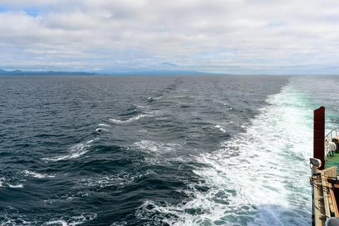 Waves create frothy patterns as a vessel cuts through the ocean under soft mo Stock Photos