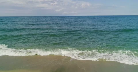 Waves crushing into the golden sand beach Stock Footage 157750228