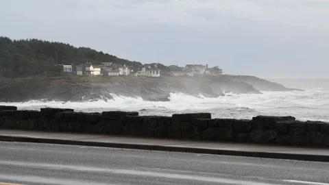 Waves crushing on the rocks next to a group of houses, next to the road Stock Footage 270804763