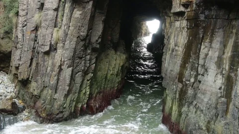 Waves crushing through Remarkable cave rock tunnel Stock Footage 71765115