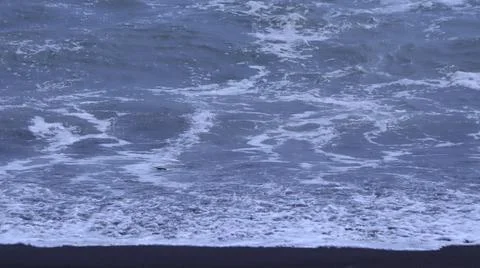 Waves on a Dark Sandy Beach Stock Photos