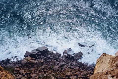 Waves of deep blue break on rocks of all shades of brown. Tourism and travel. Foto stock