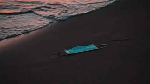 The waves drag away a mask lying on the shoreline, Coronavirus, Covid-19 Stock Footage 150349674