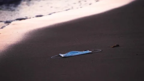 The waves drag away a mask lying on the shoreline, Coronavirus, Covid-19 Stock Footage 150349678