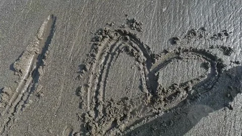 Waves erase the writing I love you on the beach sand Stock Footage 289701413