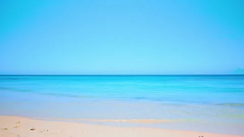 Waves float across a blue ocean lagoon towards a white sand sea beach. 스톡 동영상 277413498